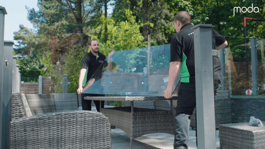 moda installers lifting glass top onto outdoor dining table 